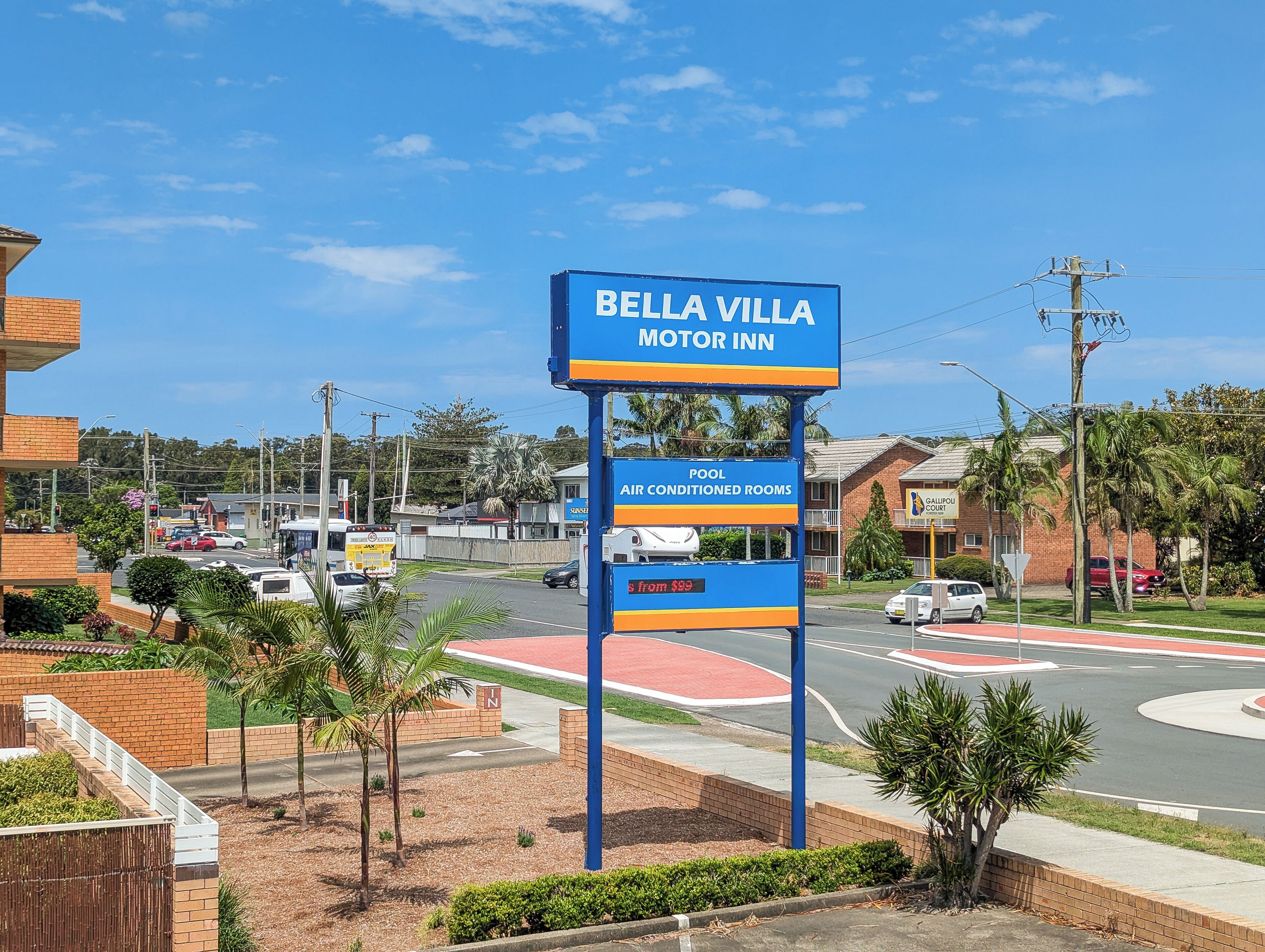 A Bella Villa Motor Inn sign with amenities including a pool and air-conditioned rooms.