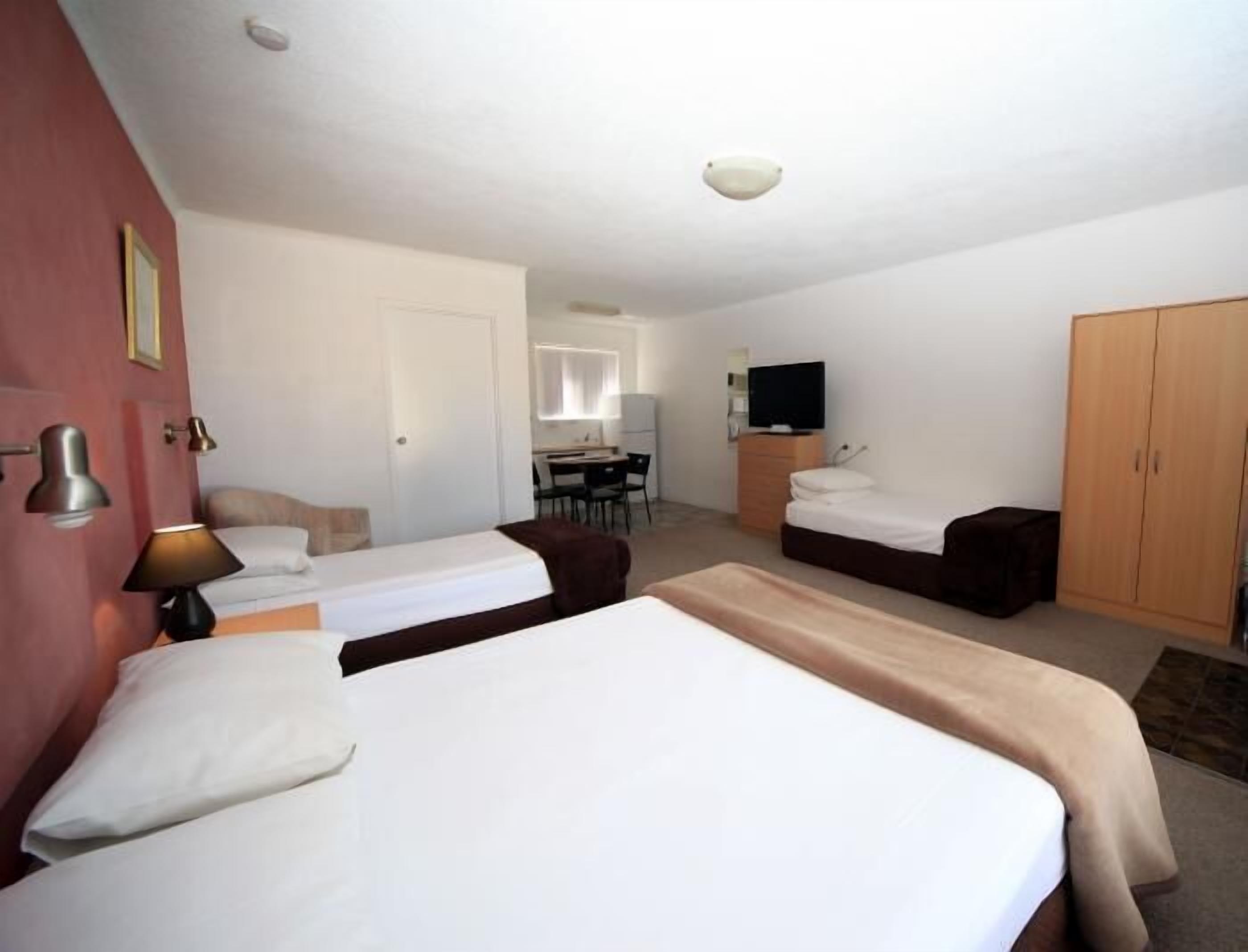 A hotel room with two beds, a desk, a television, and a wardrobe.
