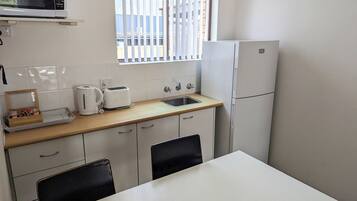 A compact kitchen with a microwave, toaster, kettle, and sink.