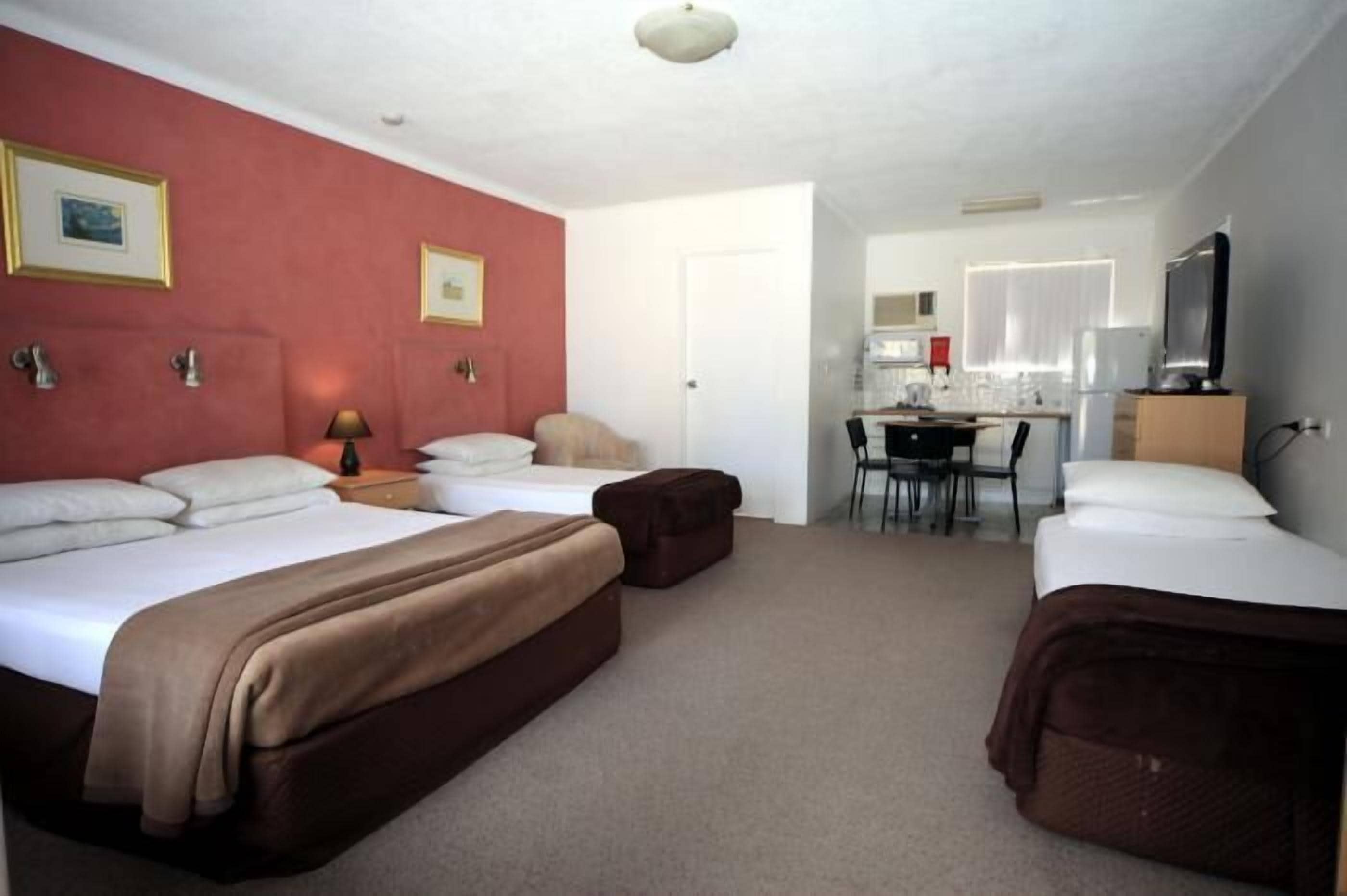 A hotel room with two beds, a desk, and a chair.