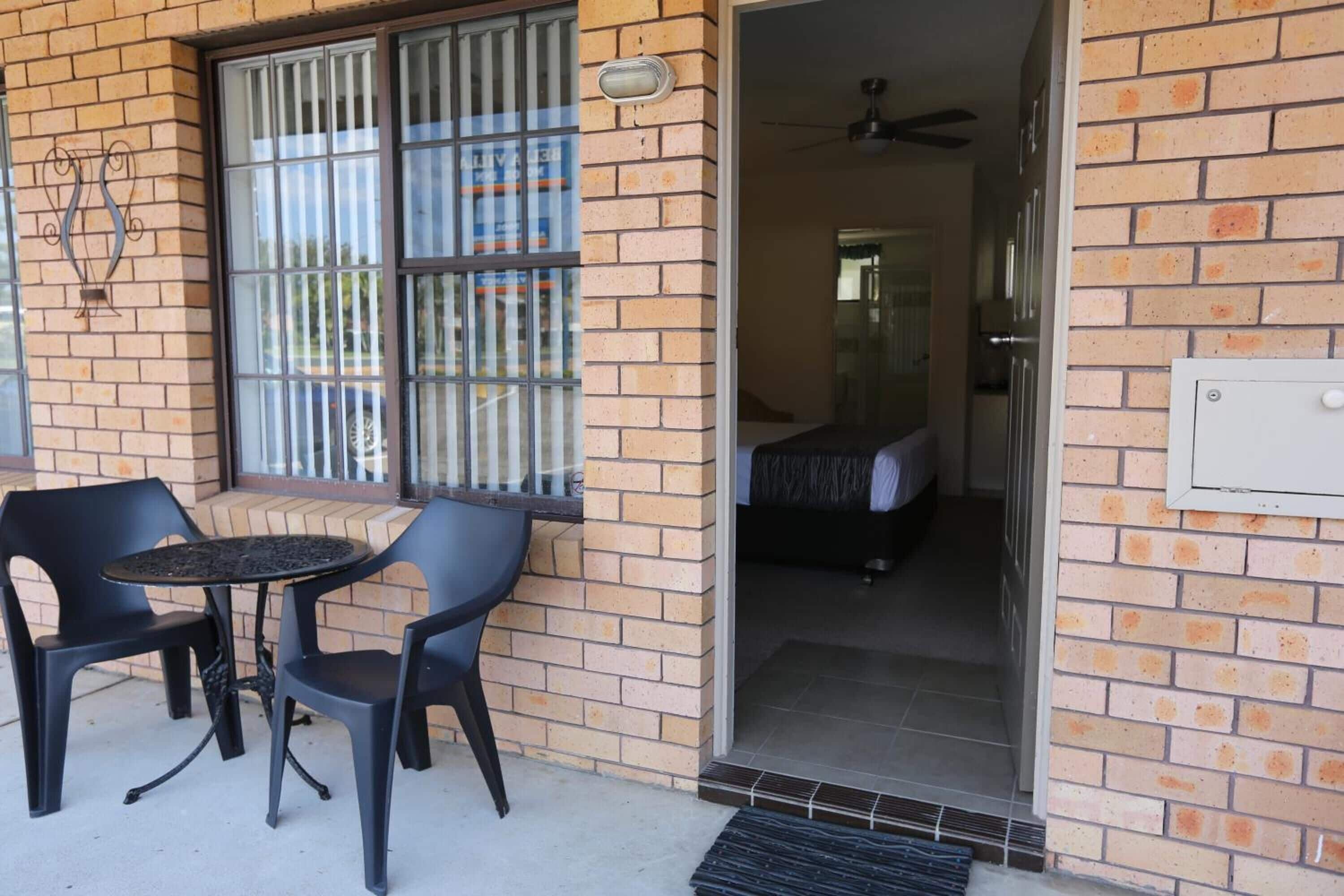 A brick exterior with a glass door leading to a room with a bed and a ceiling fan.