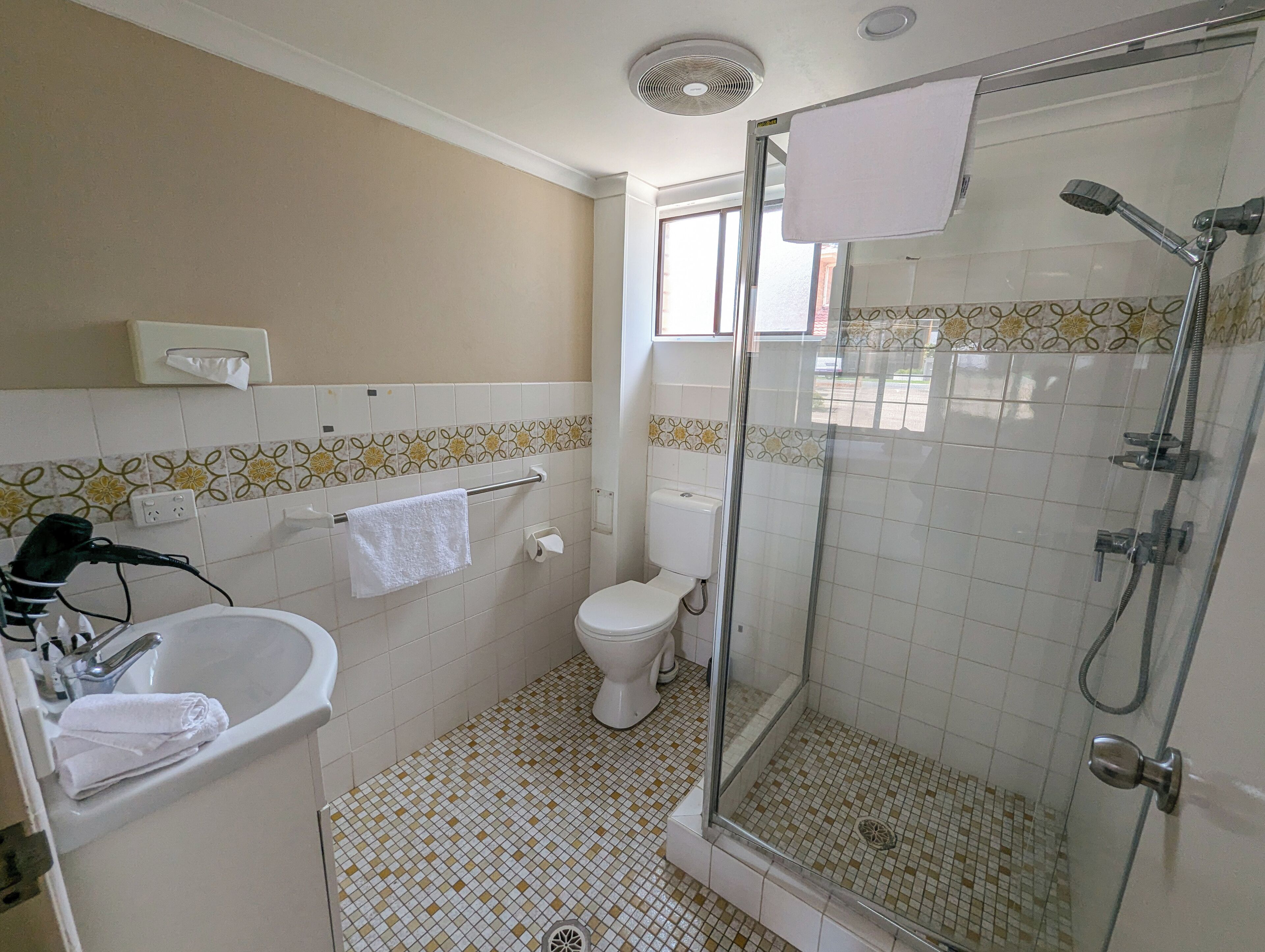 A bathroom with a glass-enclosed shower, a toilet, and a sink with a towel on it.