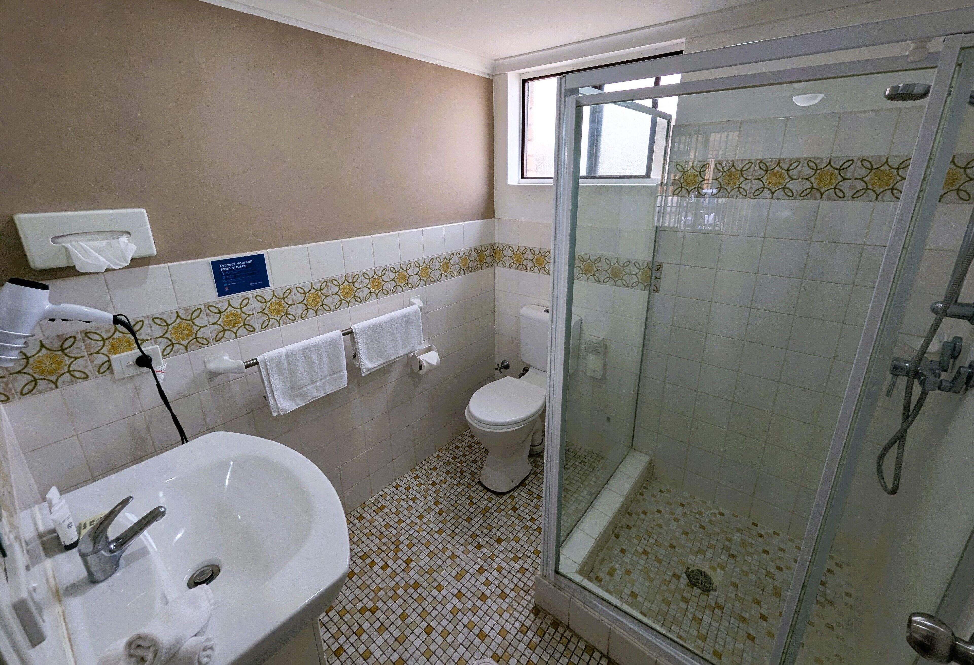 Casa de banho com lavatório, sanita e cabine de duche com vidro.