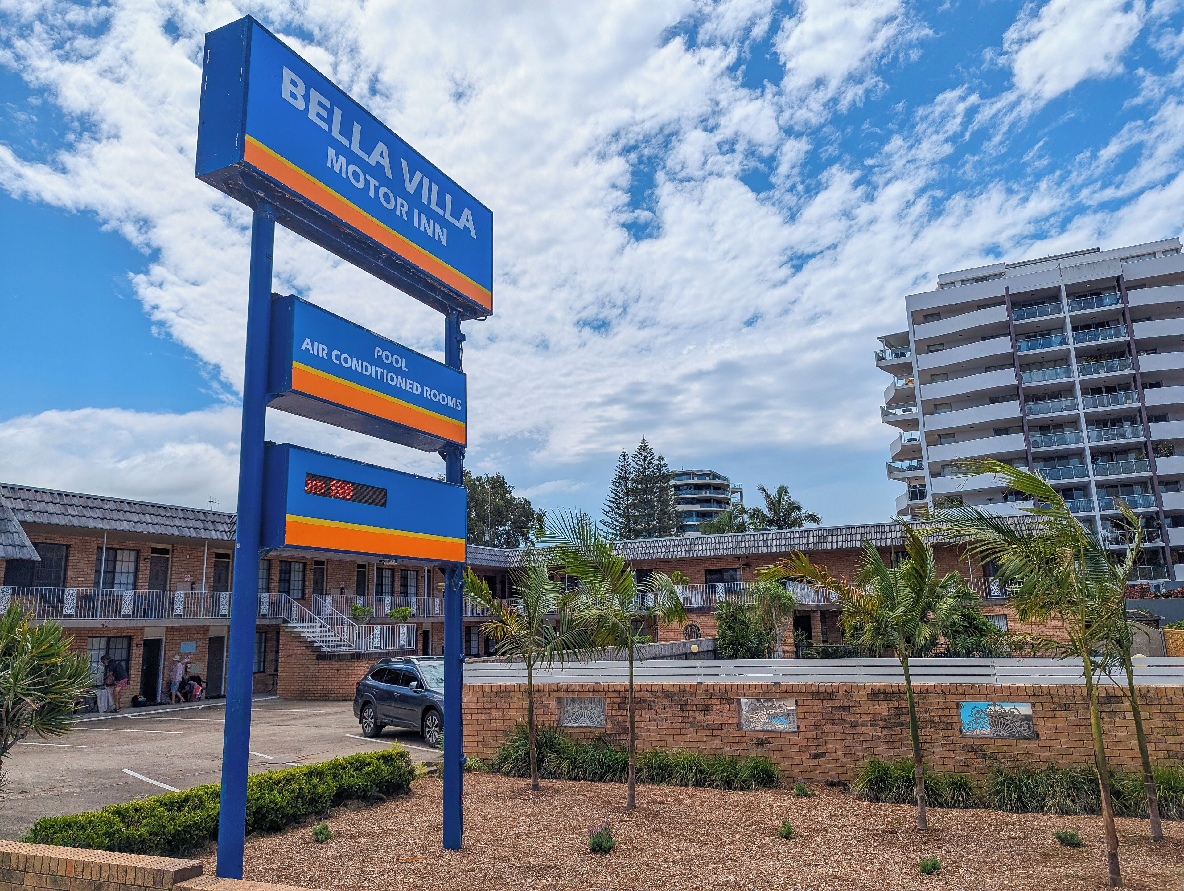 A Bella Villa Motor Inn sign with amenities including air-conditioned rooms and a pool.