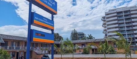 A Bella Villa Motor Inn sign with amenities including air-conditioned rooms and a pool.