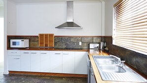 A modern kitchen with white cabinets, a built-in microwave, a toaster, and a stainless steel sink. - Bay Beach Motel (Byron Bay)