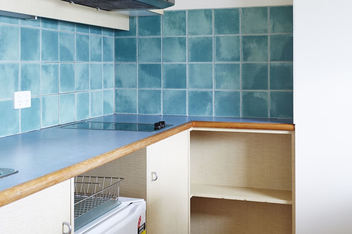 Una cocina compacta con microondas, un refrigerador pequeño y un revestimiento azul de azulejos.