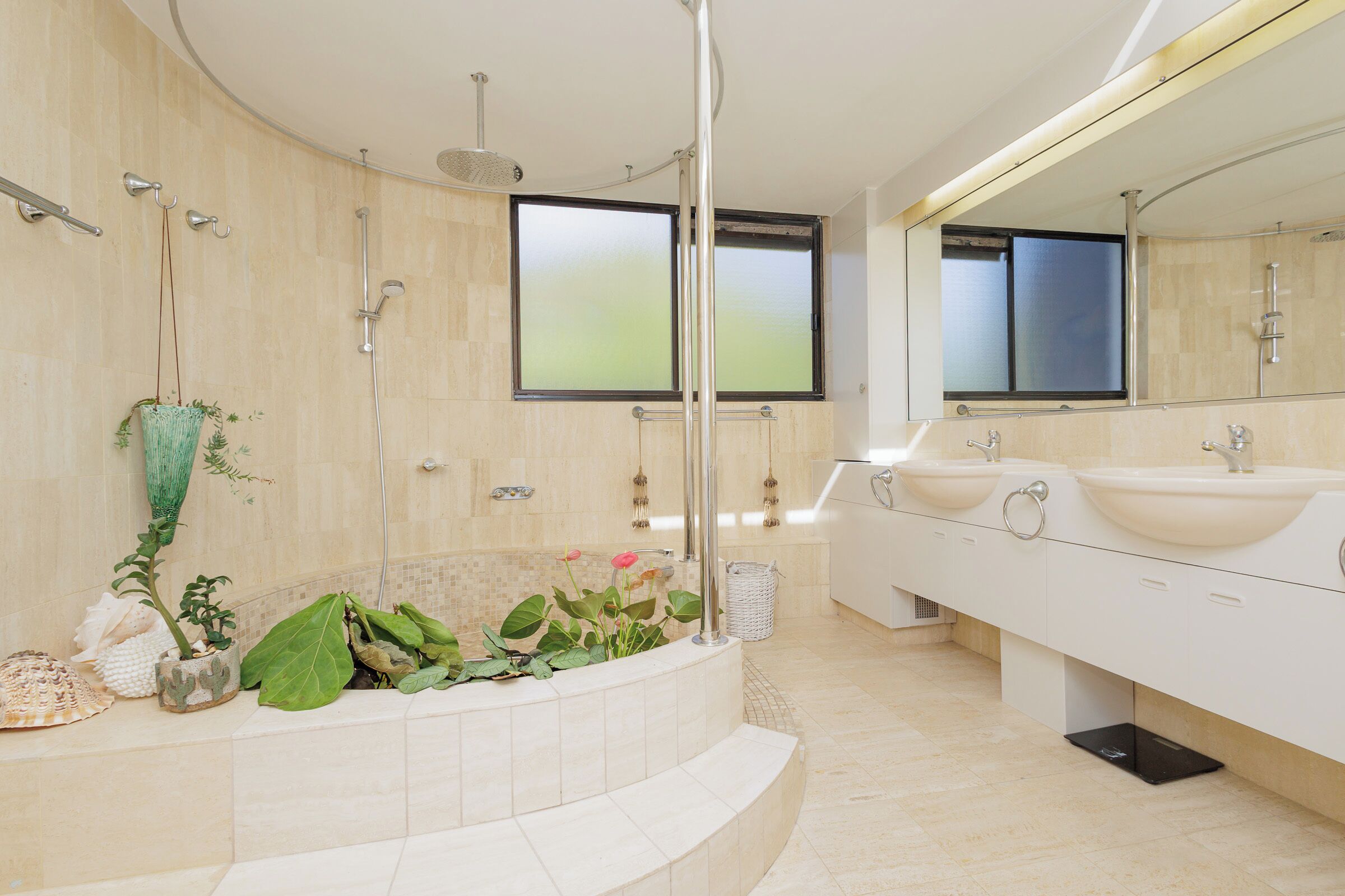 A modern bathroom with a large bathtub, two sinks, and a large mirror.