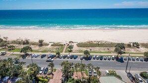 Un estacionamiento frente a la playa, con coches y una carretera que lleva a la orilla.