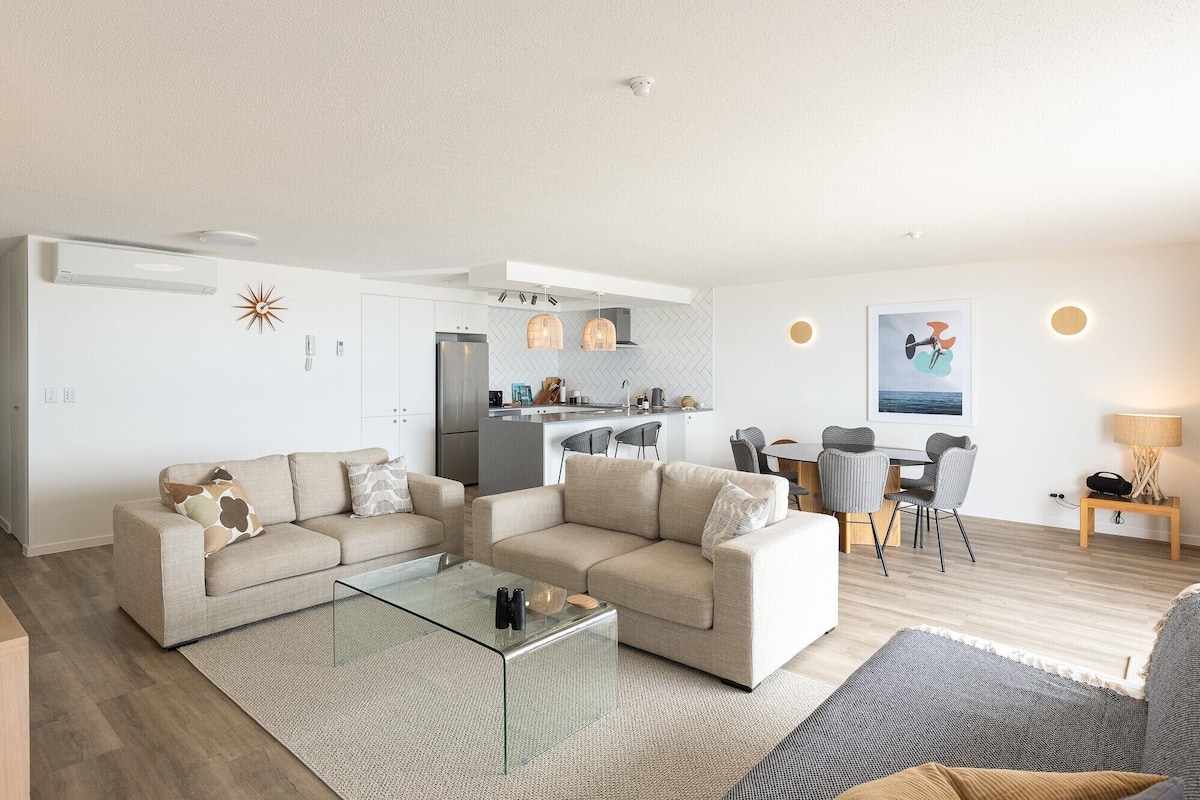 Un salon moderne comprenant un canapé, une table basse en verre et un coin repas avec des chaises et une table.