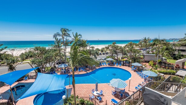Zona de piscina en un resort con vista a la playa y al océano.
