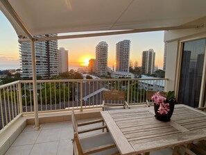 Un balcón con vistas a rascacielos y al atardecer.