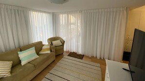 A living room with a sofa, armchair, and a flat-screen TV. - Seychelles on Main Beach (Main Beach)