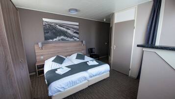 Een hotelkamer met een bed, een bureau, een stoel, een schilderij aan de muur en een deur.