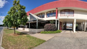 A hotel with a red and white exterior, a covered entrance, and a sign indicating a vacancy. - Hume Inn Motel Albury CBD (South Albury)