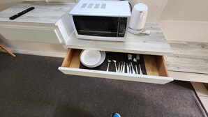 A compact kitchen area with a microwave, a small sink, and a drawer with utensils. - Hume Inn Motel Albury CBD (South Albury)