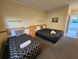 Habitación de hotel con dos camas, cada una con una colcha estampada y una toalla blanca. Hay una mesita de noche entre las camas y un cuadro en la pared.