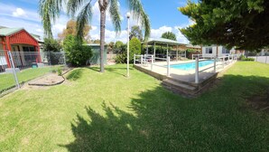 A backyard with a swimming pool, a covered patio, and a fenced area. - Hume Inn Motel Albury CBD (South Albury)