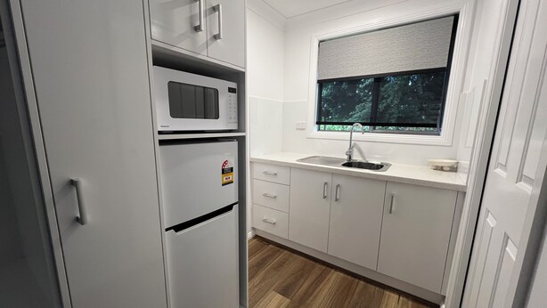A modern kitchen with a built-in microwave, refrigerator, and sink. - Almond Inn Motel (East Tamworth)