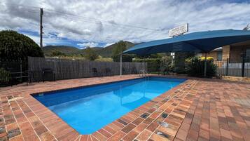 A swimming pool with a brick patio, a covered seating area, and a sign for the "Almond Inn Motel".
