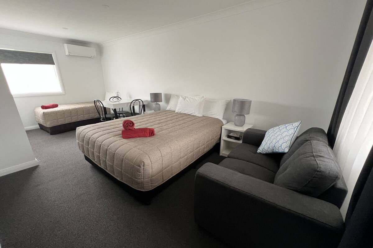 A hotel room with a large bed, a sofa, a desk, and a chair.