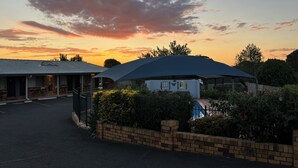 A building with a covered outdoor area, a brick wall, and a parking lot. - Almond Inn Motel (East Tamworth)