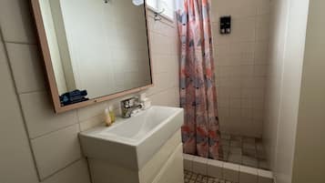 Un baño con lavamanos, espejo y ducha.