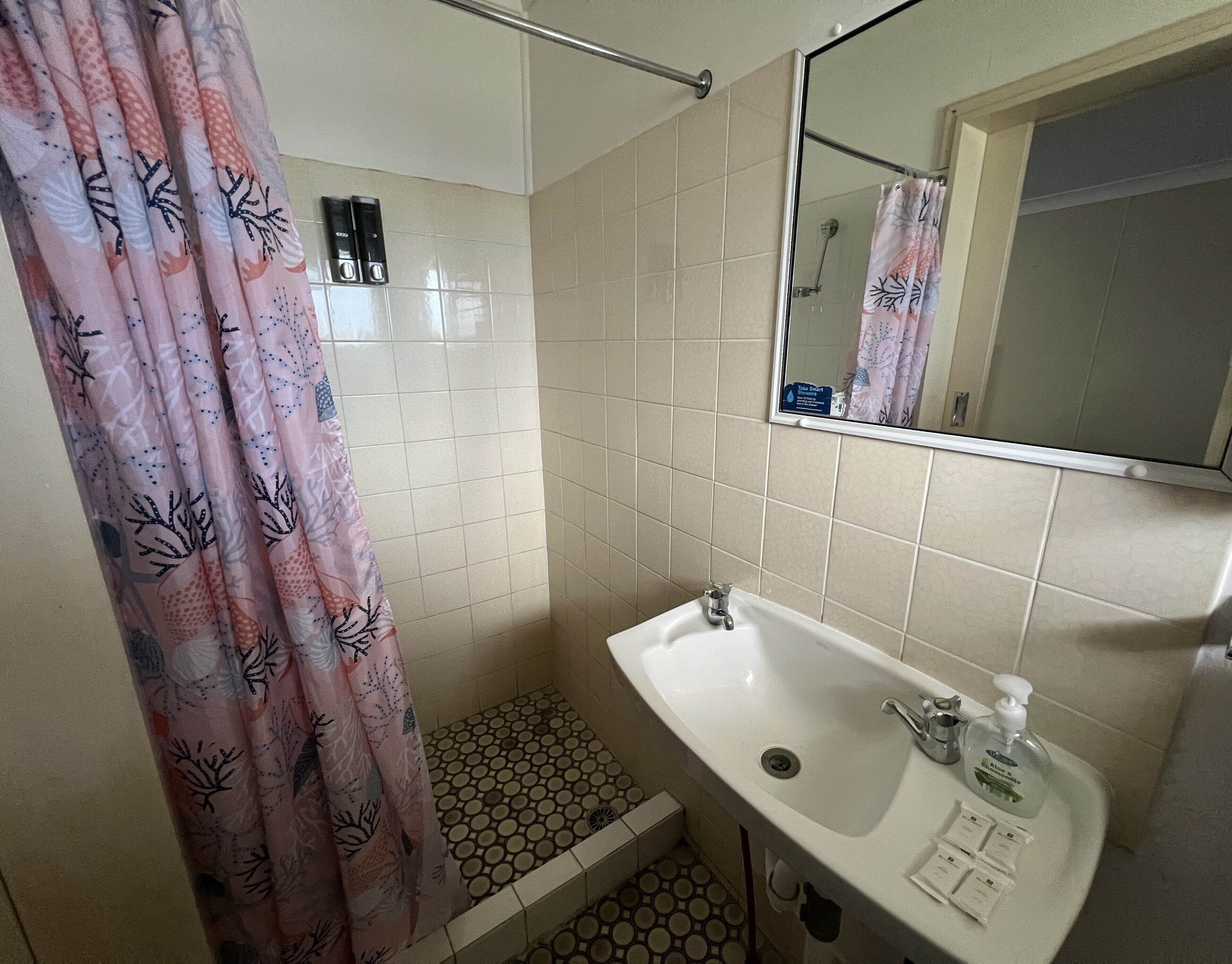 A bathroom with a shower, toilet, sink, and a mirror.