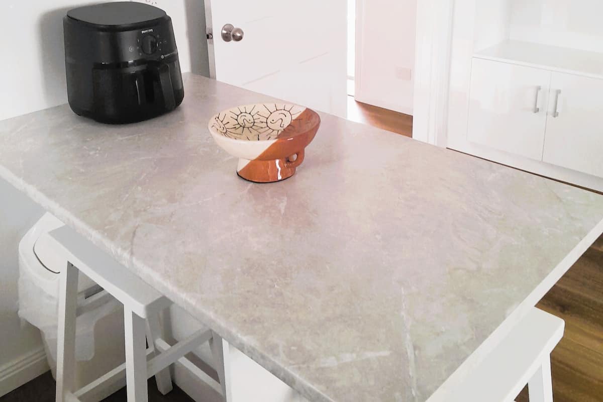 A kitchen with a white countertop, a coffee maker, and a bowl.