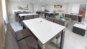 A spacious living area with a dining table, sofas, and a kitchen in the background. - Almond Inn Motel (East Tamworth)