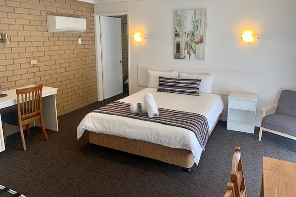 A hotel room with a large bed, a desk, a chair, and a couch.