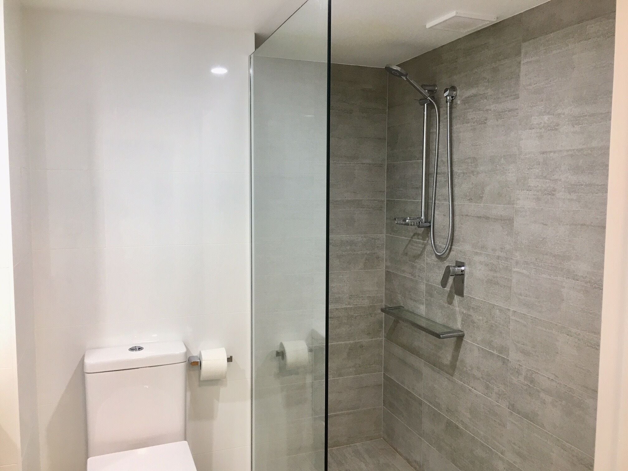Ein modernes Badezimmer mit Duschkabine aus Glas, Toilette und einer Glaseinteilung.
