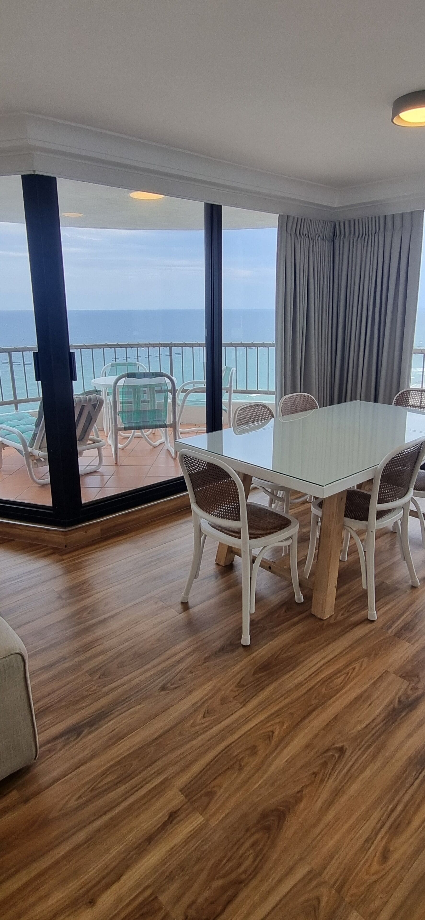 Un balcon avec une table et des chaises, donnant sur la mer.