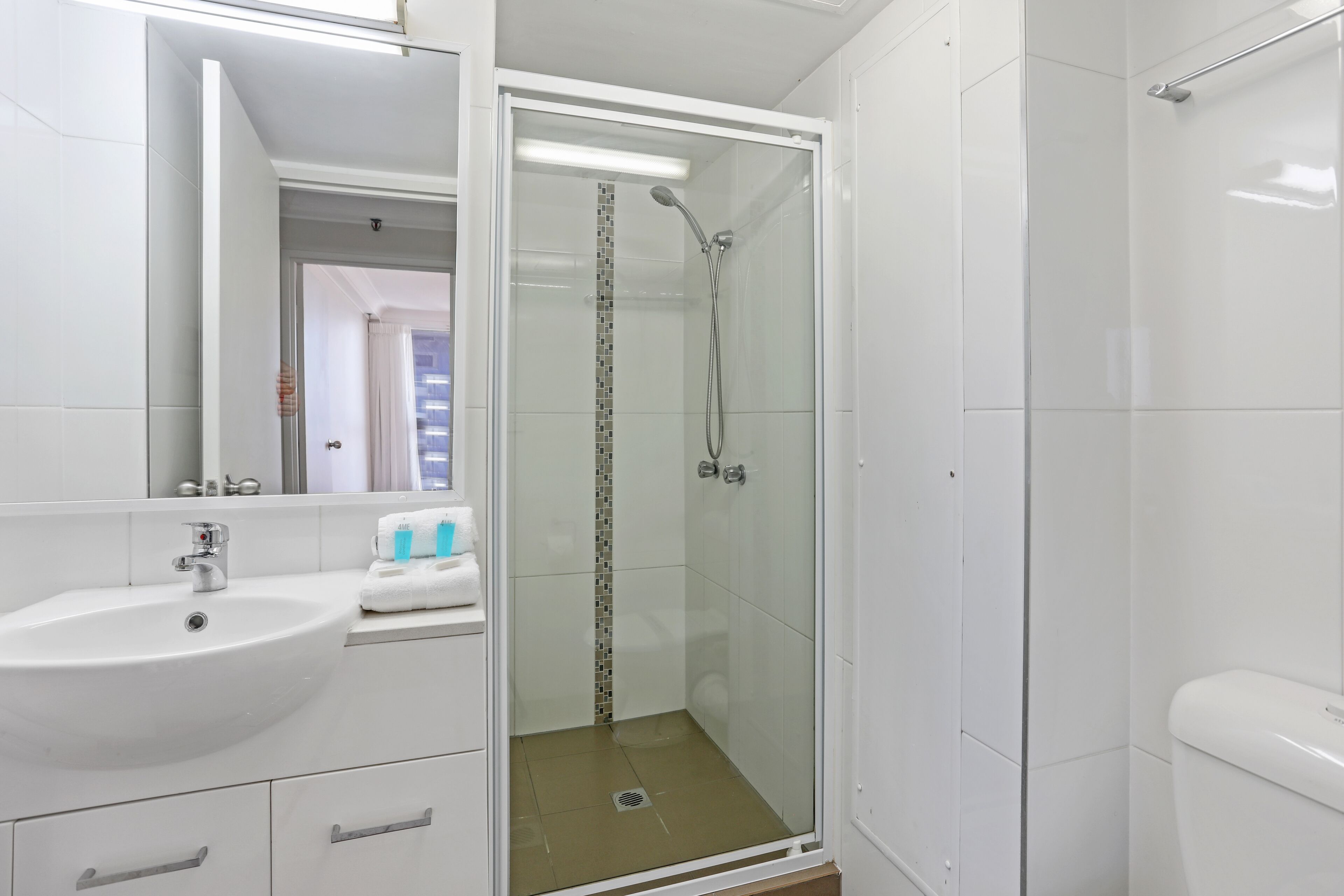 A modern bathroom with a glass-enclosed shower, a white sink, and a mirror.