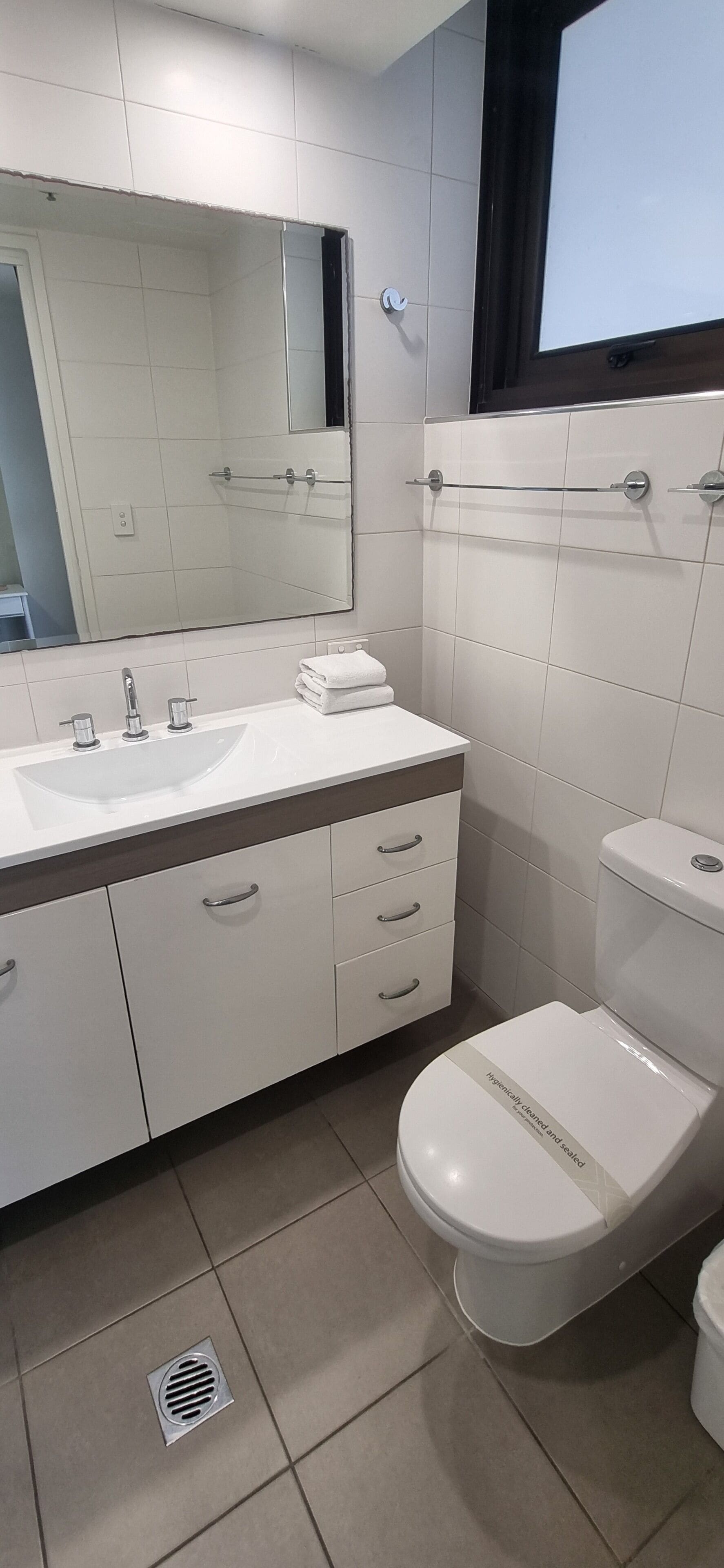 A modern bathroom with a white sink, mirror, and toilet.