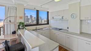 A modern kitchen with white cabinets, a built-in stove, and a large window overlooking a cityscape.