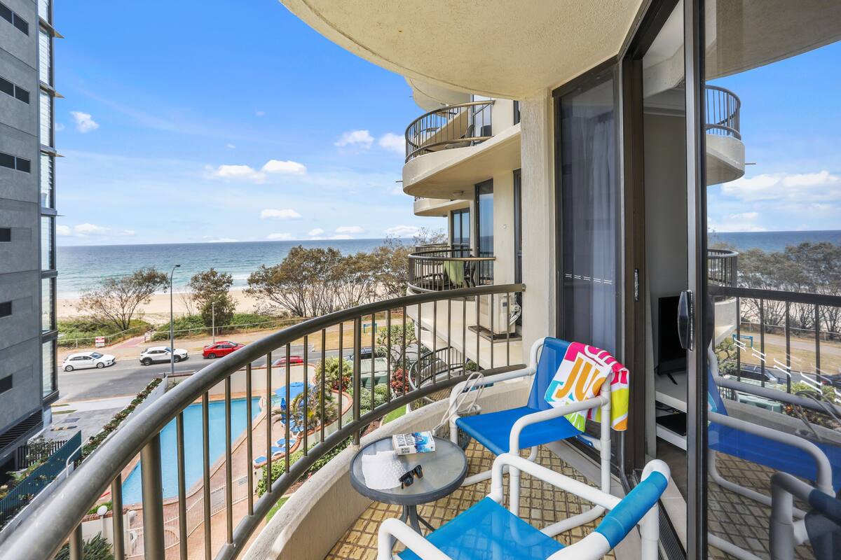 Een balkon met uitzicht op een zwembad, een stoel en een tafel.