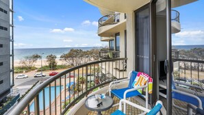 A balcony with a pool view, a chair, and a table.