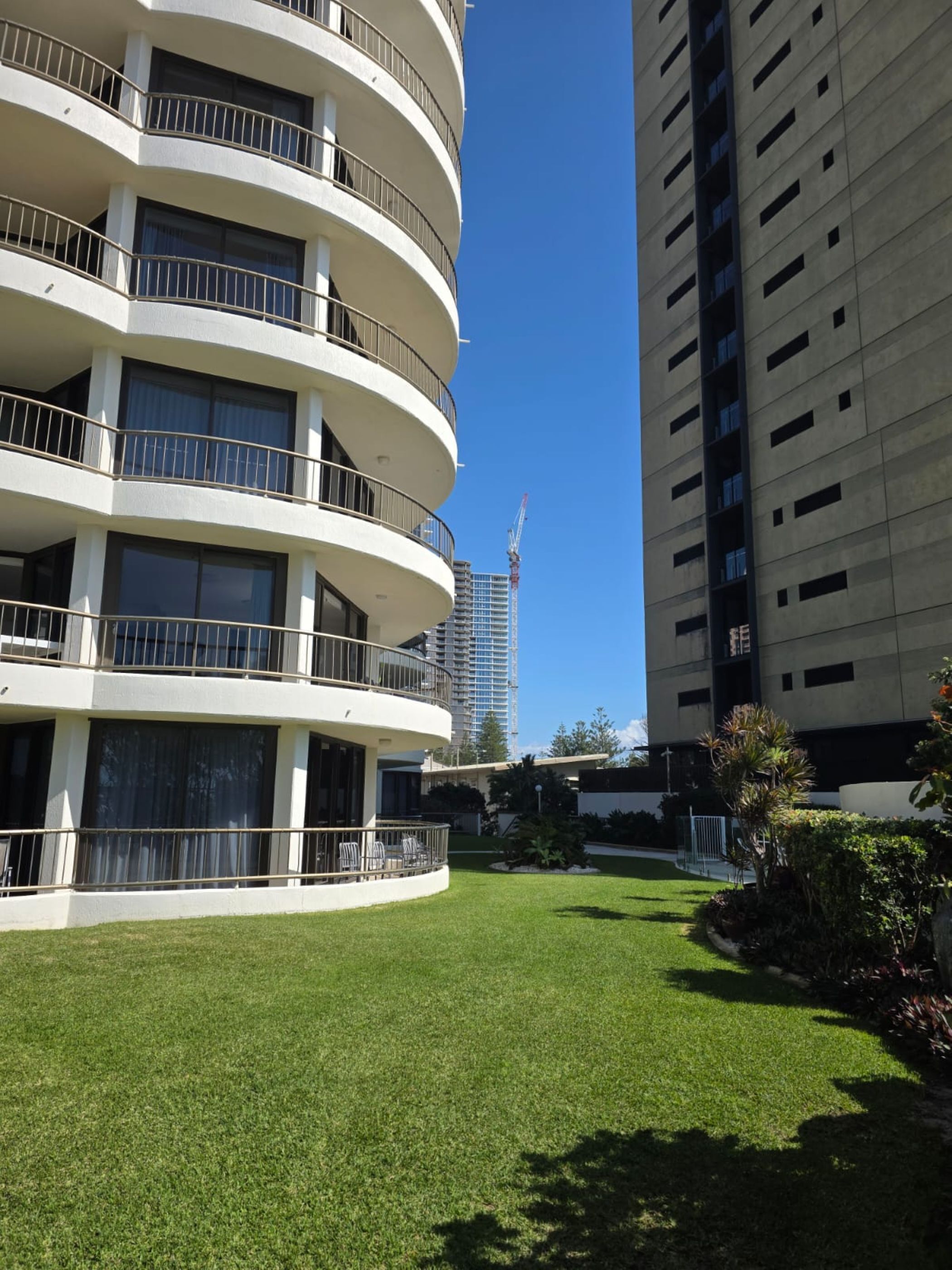 A modern building with multiple balconies and a well-maintained lawn.