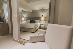 A hotel room with a bed, bedside tables, a chair, and a mirror. - Allure Bonbon by Karisma Hotels & Resorts (Cartagena)