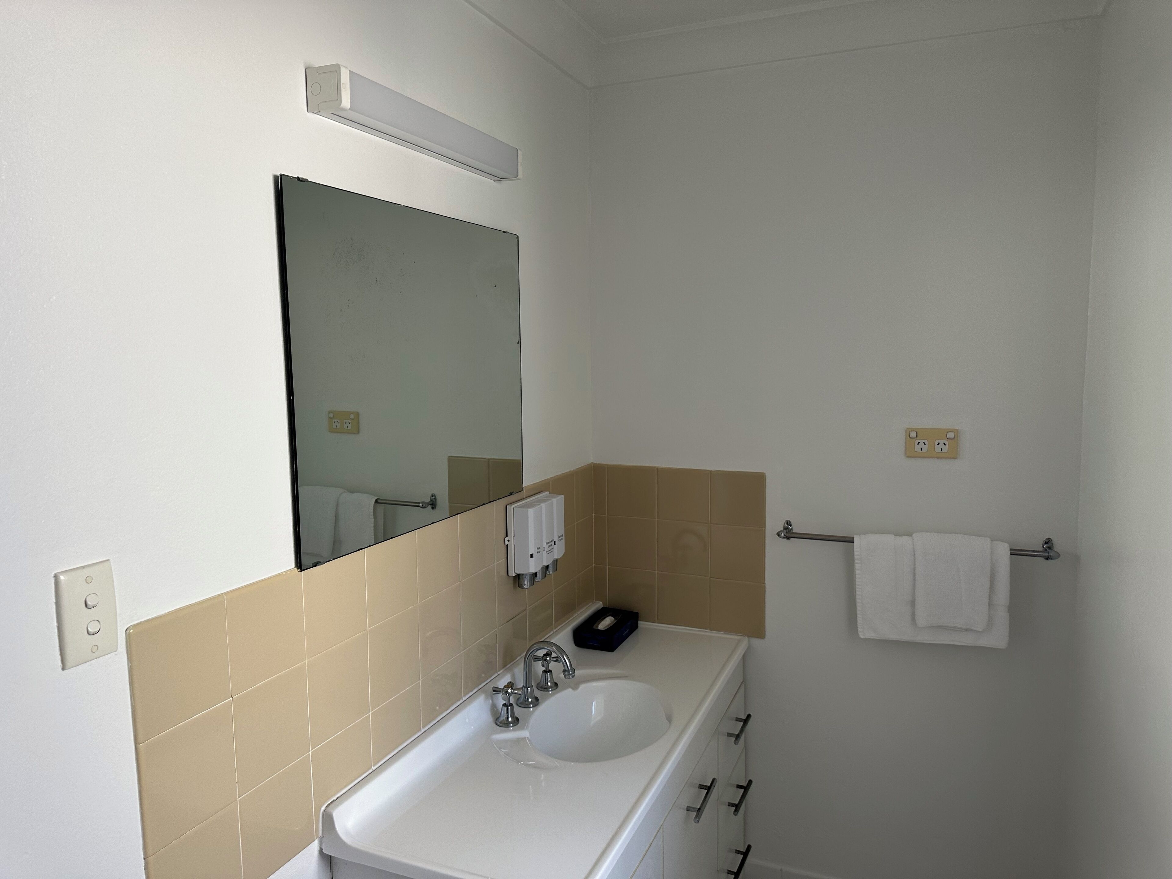 A bathroom with a white sink, a mirror, and a towel rack.
