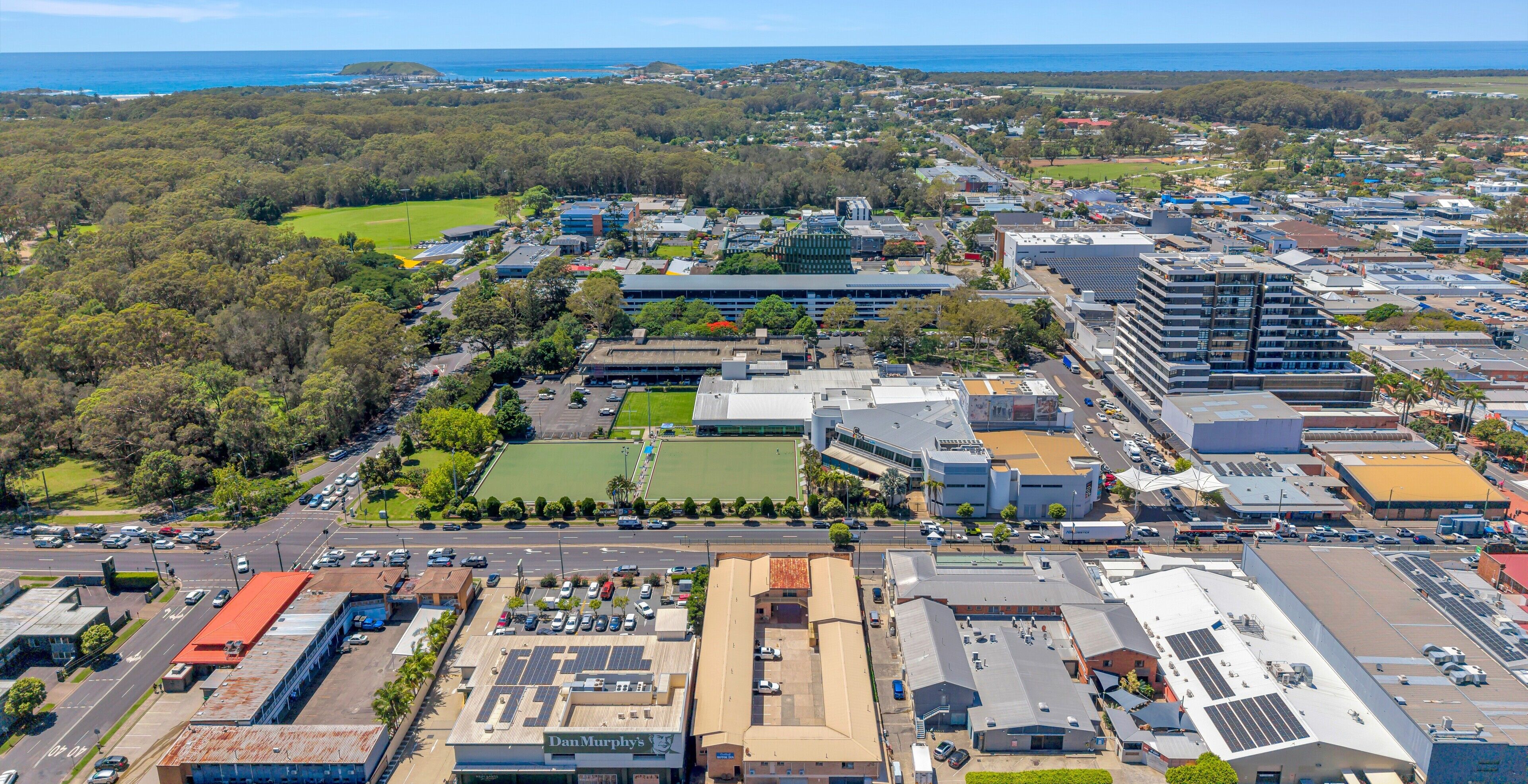 An aerial view of a cityscape with a mix of commercial buildings, roads, and green spaces.