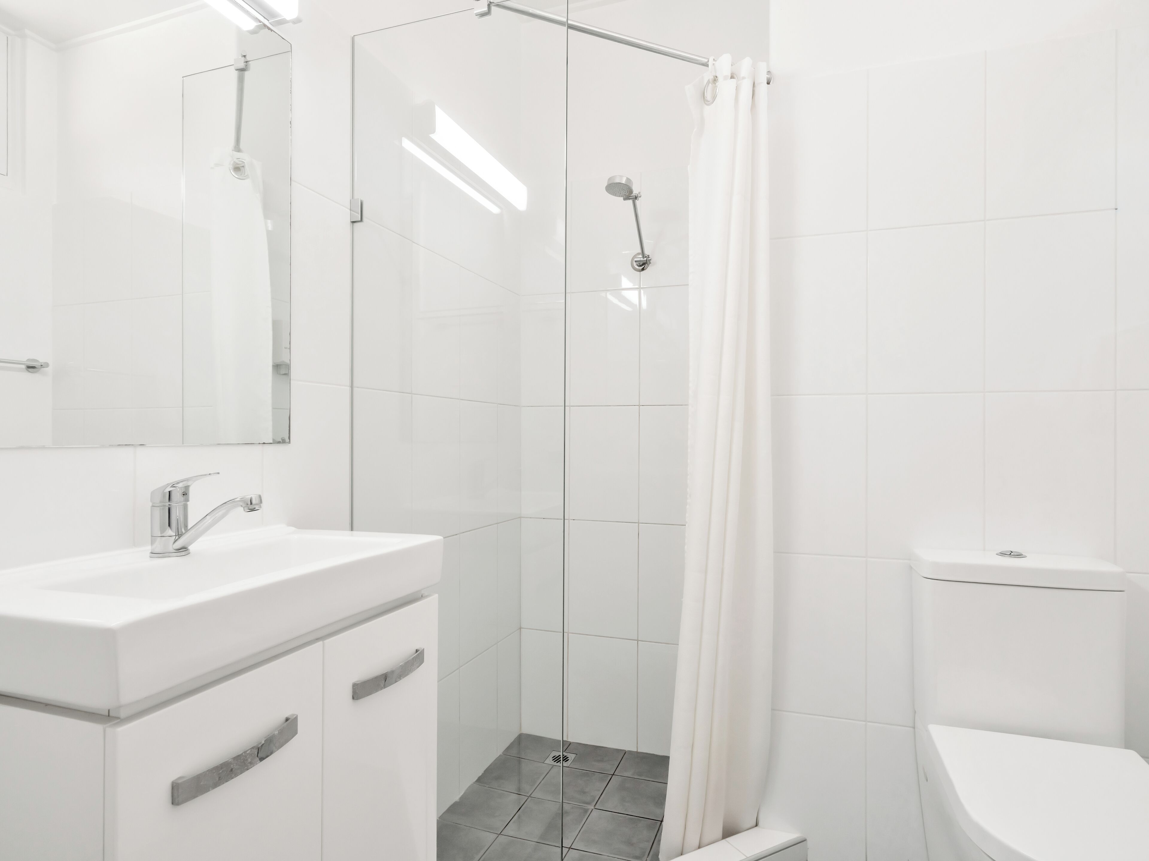 Ein modernes Badezimmer mit einer Glasdusche, einem weißen Waschbecken und einer Toilette.