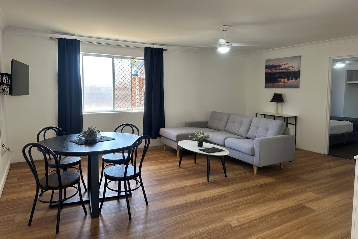 A modern living room with a dining table, sofa, and a small coffee table.