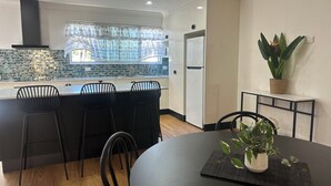 Una cocina moderna con una isla central, sillas negras, una mesa de comedor y una planta en maceta.