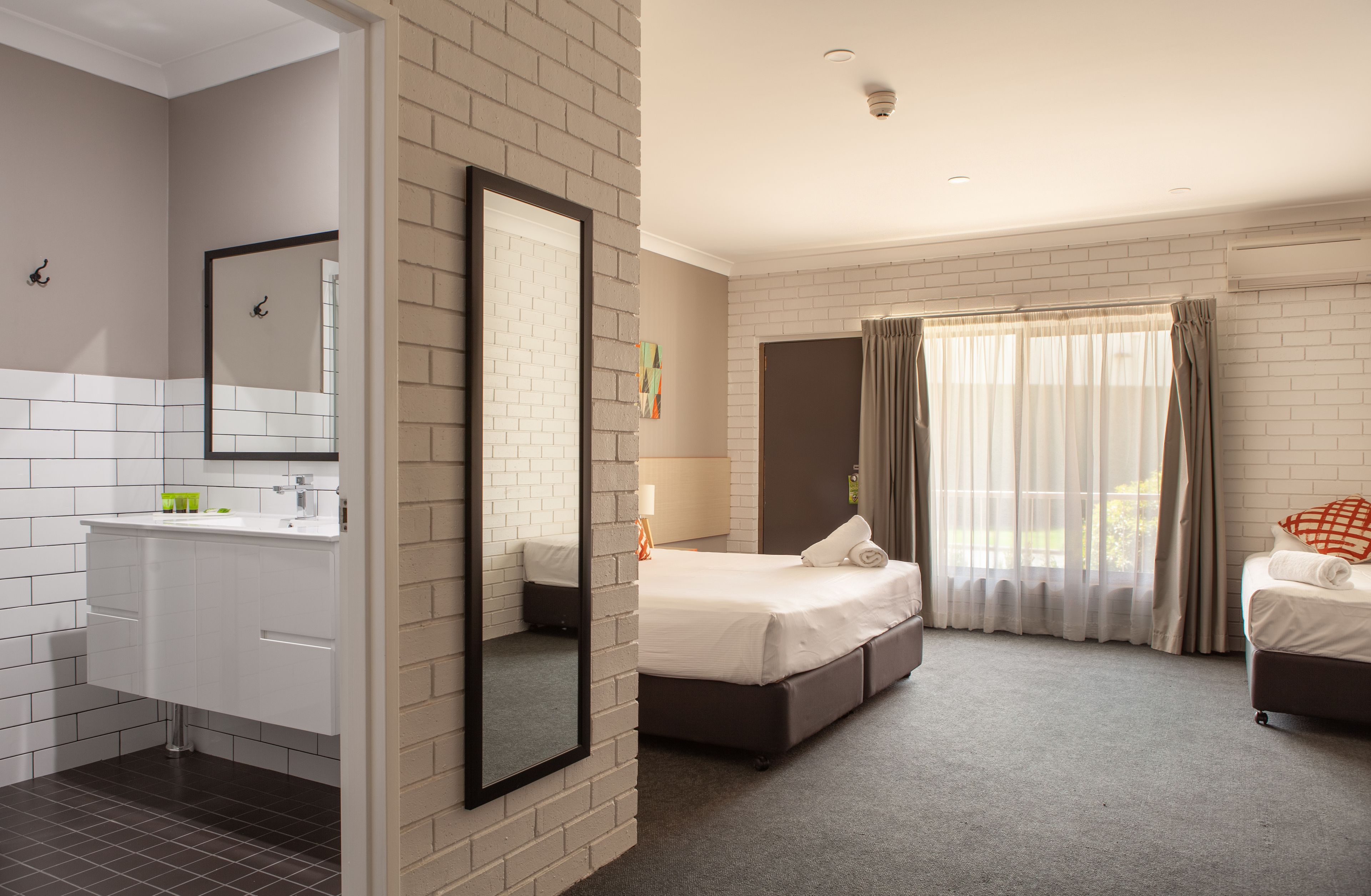 Ein Hotelzimmer mit Bad, einem Bett, einer Couch und einem großen Fenster mit Vorhängen.