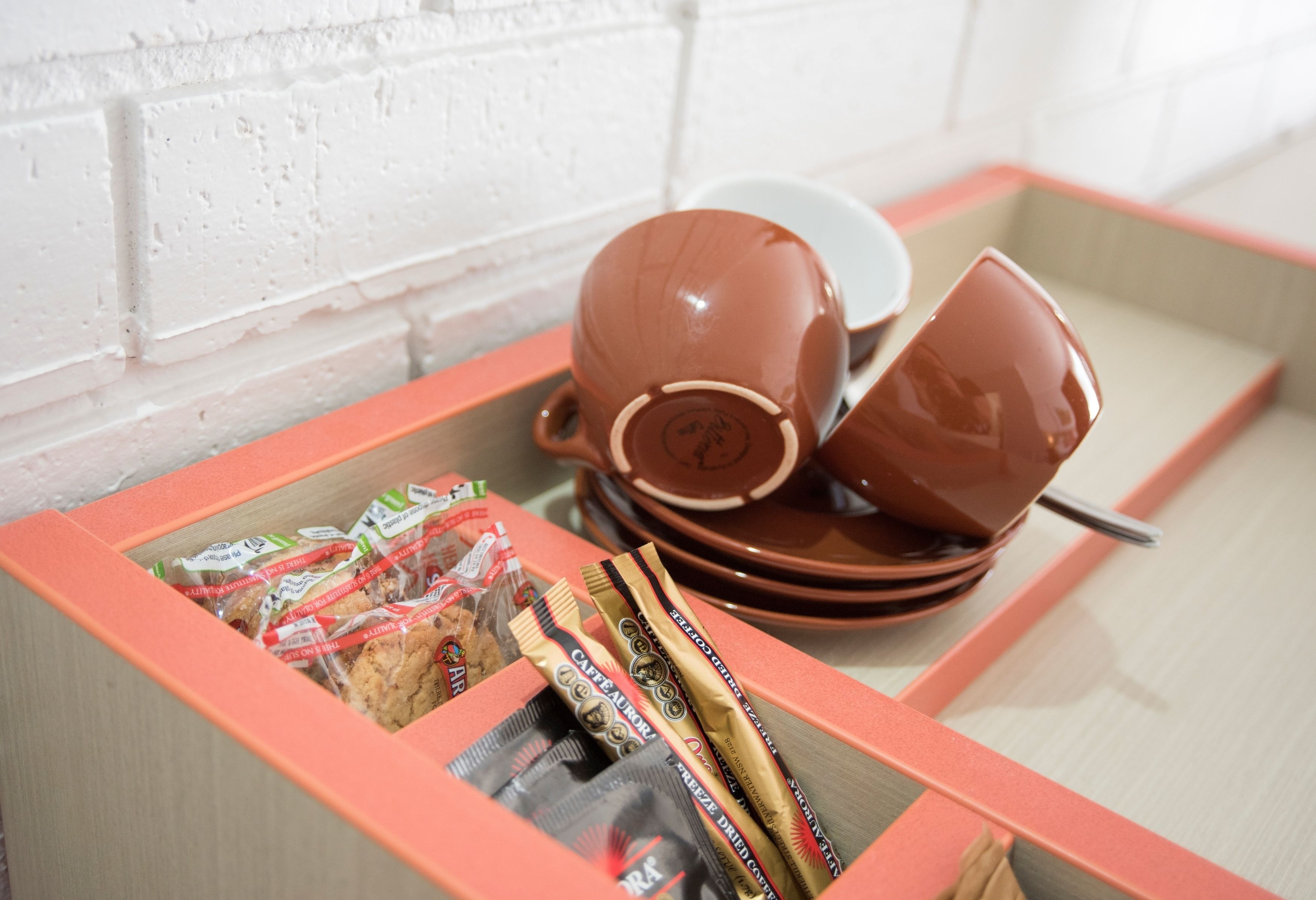A kitchen area with a countertop, a coffee maker, a cup, and a box of coffee pods.