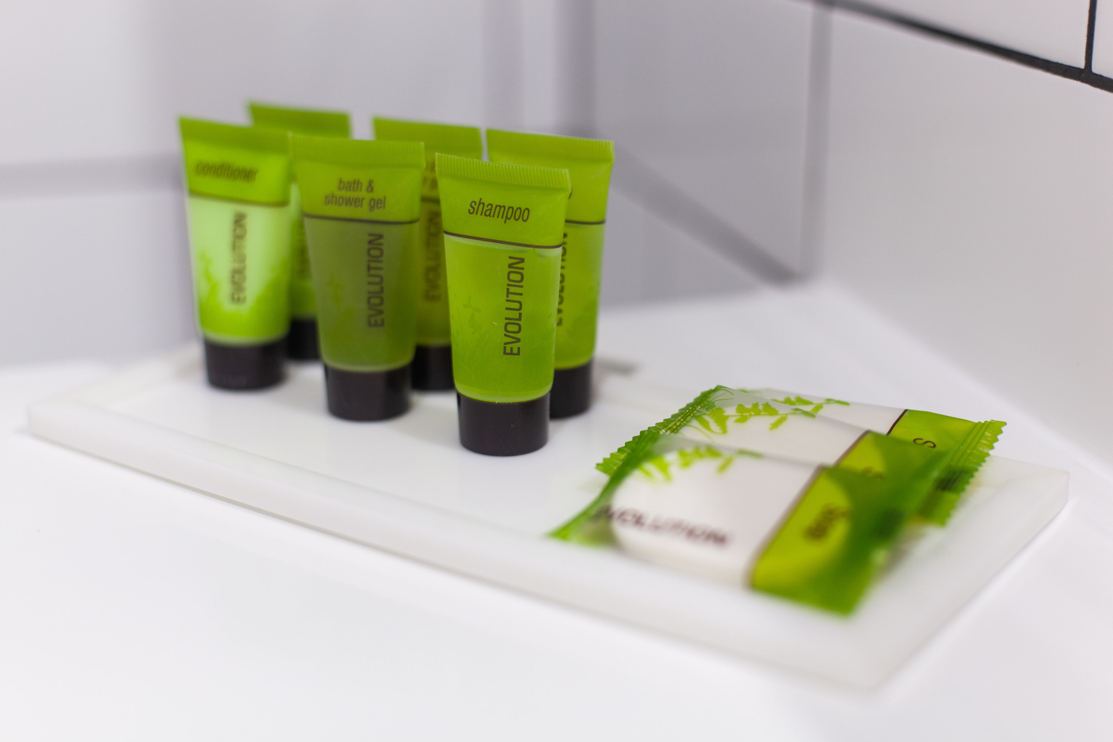 A set of green tubes labeled 'EVOLUTION' on a white surface, likely in a bathroom setting.