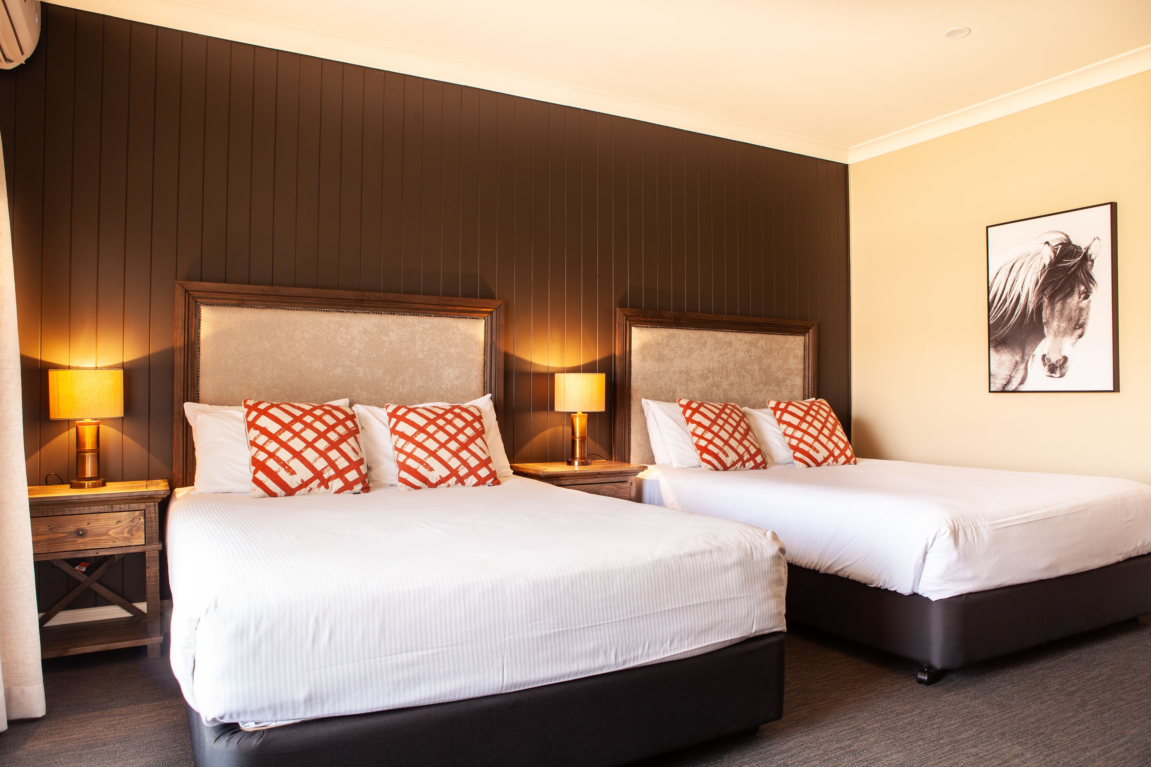 Quarto de hotel com duas camas, cada uma com cabeceira, abajures e um quadro na parede.