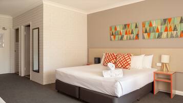 A hotel room with a large bed, a bedside table, a nightstand, and a wall with colorful artwork.